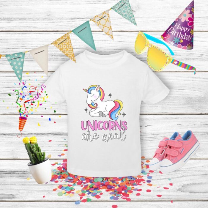 Tricou alb cu unicorn și accesorii festive.